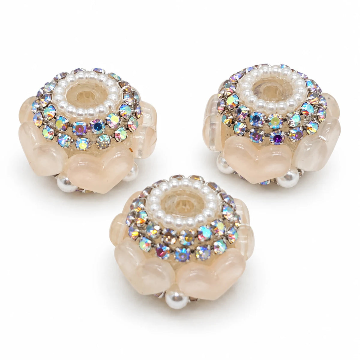 Three apricot acrylic heart barrel beads with silver-tone rhinestone trim and pearl-like accents on a white background