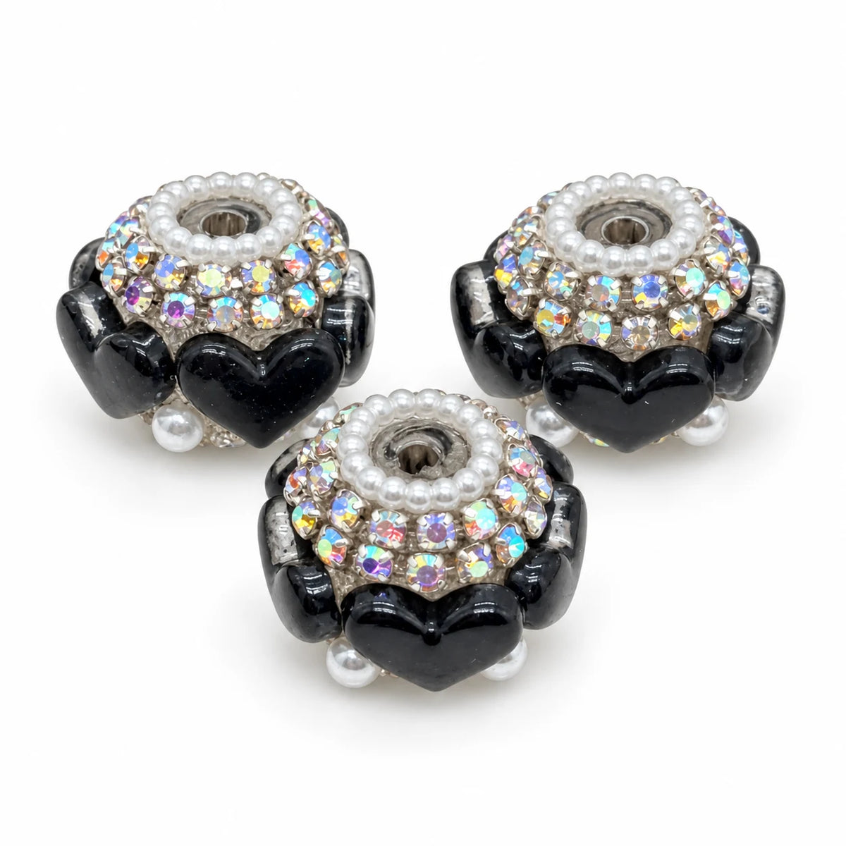 Three black acrylic heart barrel beads with silver-tone rhinestone trim and pearl-like accents on a white background