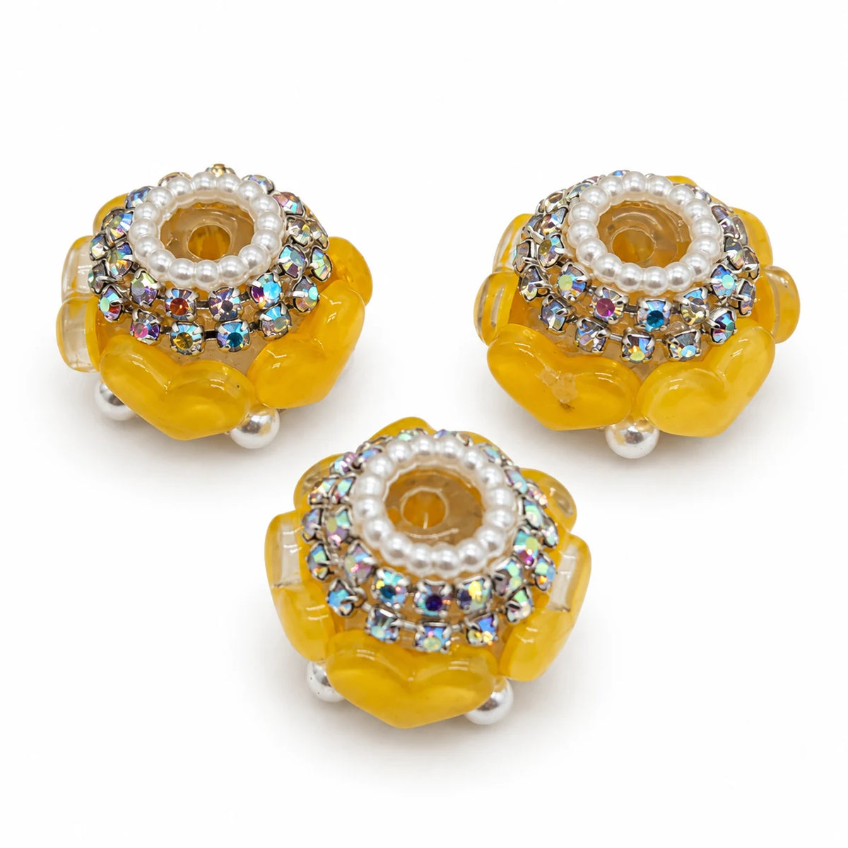 Three bright yellow acrylic heart barrel beads with silver-tone rhinestone trim and pearl-like accents on a white background