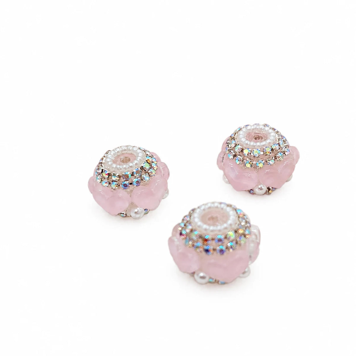 Three pink acrylic heart barrel beads with silver-tone rhinestone trim and pearl-like accents on a white background